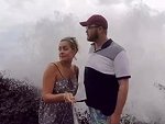 Couple Smile For A Selfie As A Wave Crashes Behind
